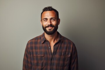 Fototapeta premium Portrait of a tender man in his 30s dressed in a relaxed flannel shirt isolated on minimalist or empty room background