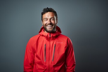 Obraz premium Portrait of a smiling man in his 30s wearing a windproof softshell in minimalist or empty room background