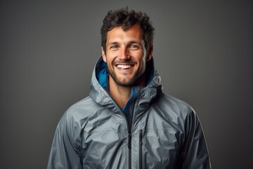 Fototapeta premium Portrait of a smiling man in his 30s wearing a windproof softshell while standing against minimalist or empty room background