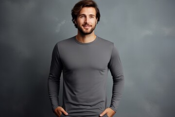 Fototapeta premium Portrait of a satisfied man in his 30s showing off a lightweight base layer while standing against minimalist or empty room background