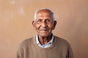 Obraz premium Portrait of a glad indian man in his 80s showing off a thermal merino wool top in front of minimalist or empty room background
