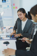 Two young businesswomen are carefully reviewing financial reports and data analysis on a desk in a modern office