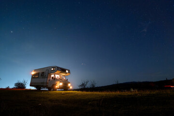 Motorhome camping in the mountains at night, under the starry sky