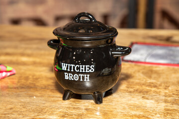 A halloween decoration of a small plastic pot with the words printed on it saying Witches Broth
