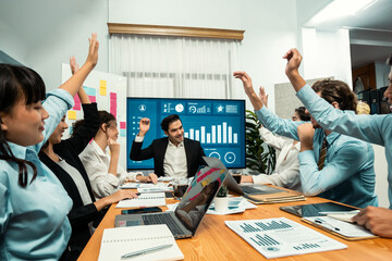 Group of happy multi ethnic businesspeople in celebratory gesture and successful teamwork after made success sales or positive financial data dashboard display on screen in meeting room. Habiliment