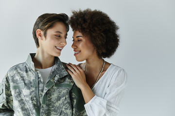 A loving farewell moment between a soldier in uniform and her supportive wife in a studio.