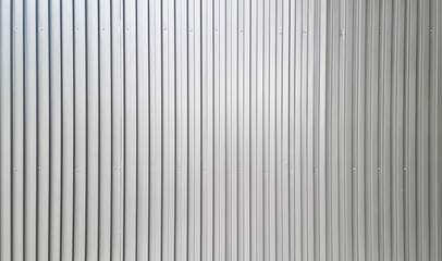 real chrome corrugated metal sheet wall showing vertical pattern, bolts, screw. modern industrial grey metal sheet wall facade. wide surface of grey aluminum wall texture use for design.