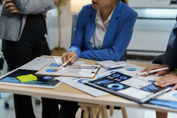 Business team in a meeting analyzing financial charts and graphs on desk with calculator and digital tablet