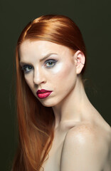 Fototapeta premium Woman with red hair and red lipstick poses for a photo. She has thick, beautiful hair. Fashion and beauty concept.