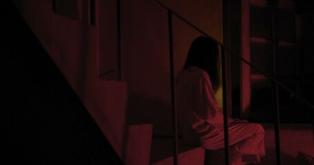 Horror scene of a mysterious Scary Asian ghost woman creepy have hair covering the face sitting on...