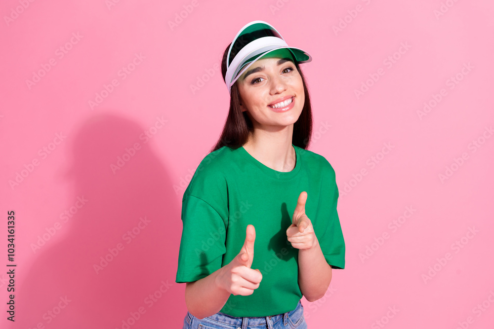 Poster Photo of charming positive woman wear green t-shirt cap pointing you two fingers empty space isolated pink color background