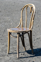 An old chair stands on a gravelled pile in the sun.