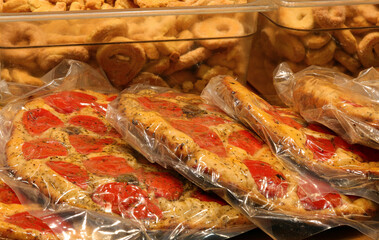 vacuum-packed packages of fragrant and spiced focaccia with red tomatoes for sale at food stalls