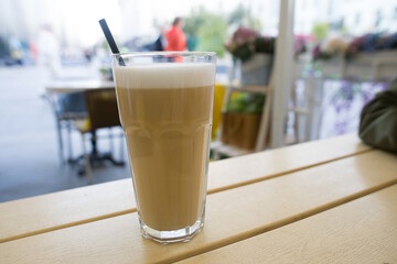 Cappuccino in a glass glass with a straw. Morning hot invigorating drink