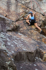 Obraz premium Image of a fit and attractive brunette girl climbing a granite rock wall