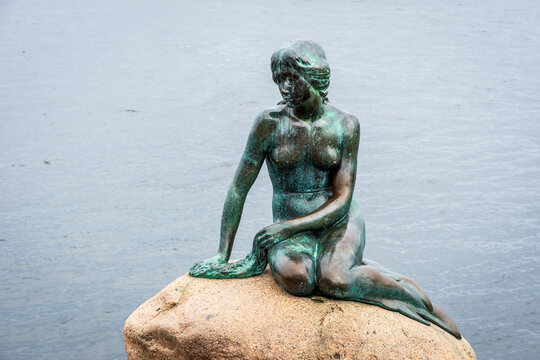 Copenhagen, Denmark - July 16, 2024: The Little Mermaid is a bronze statue by Edvard Eriksen depicting the character in the 1837 fairy tale by H.C. Andersen, displayed since 1913 on a rock by the sea.