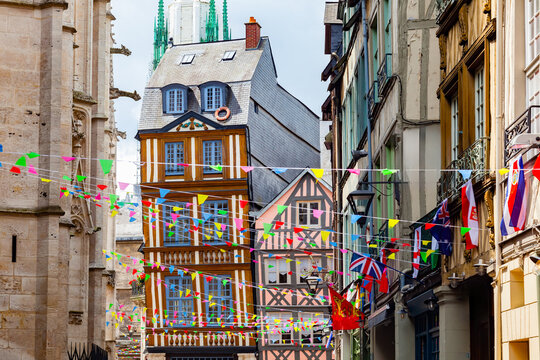 ROUEN, NORMANDY, FRANCE, JUNE 12, 2019: "House that leans", best-known timber-framed house in Rouen, shows an obvious slope, flag decoration for Armada festival and Notre-Dame Cathedral in background