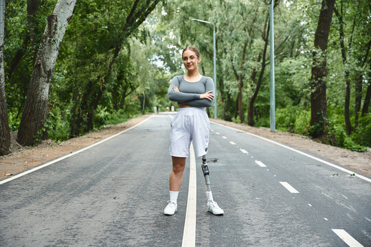 A determined young woman enjoys outdoor fitness, confidently showcasing her prosthetic leg amid lush greenery.