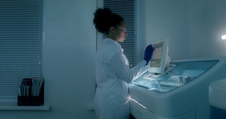 Work in a medical laboratory. A man and a woman are talking using a laptop sitting at a table with...