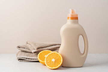 Detergent or fabric softener in plastic bottle on beige background with stack of cotton towels and...