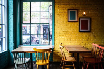 Colorful Cafe Setting with Aligned Tables and Chairs by a Sunlit Window – Modern Restaurant Interior