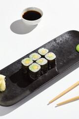 Minimalist Avocado Hosomaki Roll on Black Plate with Soy Sauce - Elegant Japanese Cuisine Photography