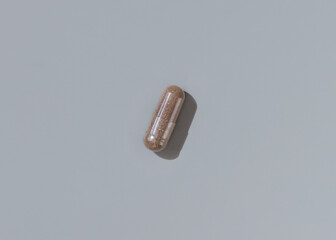 Brown Medical capsule on grey top view, hard shadows. Taking dietary supplements