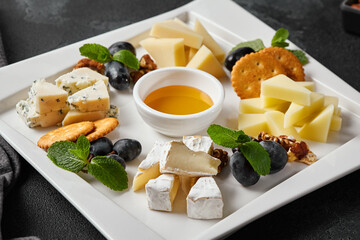 Gourmet Cheese Platter with Honey Dip and Fresh Grapes on White Ceramic Plate - High Contrast Food Photography