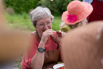 Joyful senior woman laughing at outdoor gathering with friends