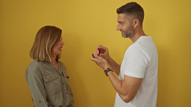 Man proposing to woman with ring on yellow background, showing surprise and rejection emotions, representing relationship moments and love