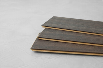 Laminate flooring pieces on grey textured surface, closeup