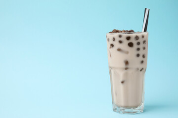 Tasty milk bubble tea in glass on light blue background, space for text