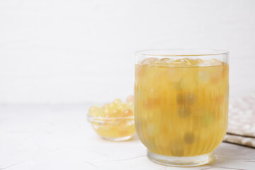 Tasty bubble tea in glass and tapioca pearls on white table, closeup. Space for text