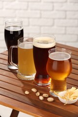 Glasses with different types of beer and snacks on wooden table