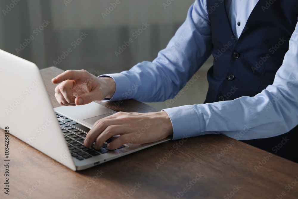 Wall mural businessman using laptop at wooden table indoors, closeup. modern technology