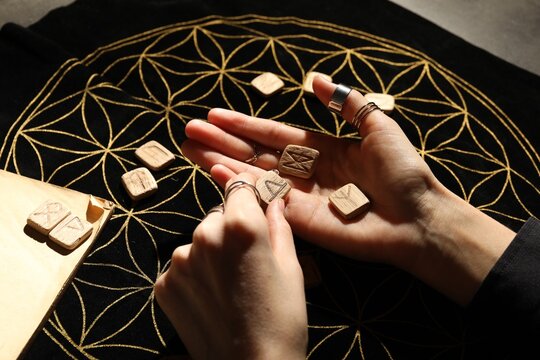 Woman with wooden runes at divination mat, closeup