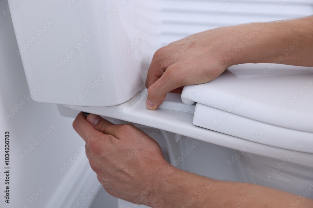 Canvas Prints Man fixing toilet seat in bathroom, closeup