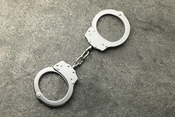 Classic chain handcuffs on grey table, top view