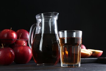 Tasty fresh apple juice and fruits on black wooden table