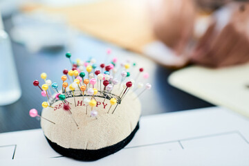 Fashion, pins and cushion for sewing in studio for manufacturing process, production and design workshop. Needle selection, textile equipment and kit on table for handmade craft and tailoring trade