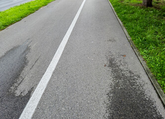 A clear, well-maintained bike lane beside green grass, perfect for cyclists and outdoor enthusiasts. The asphalt surface is smooth for safe riding.