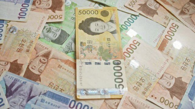 South korean banknotes including 50000 won, 10000 won, and 5000 won denominations spread out closely, showcasing traditional designs and significant historical figures.