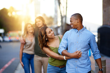 City, walking and couple of friends for travel, vacation journey and bonding together for reunion. Happy people, men and women with hug for relationship, double date and group by sunshine in downtown