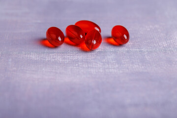Close-up of red transparent pills on a concrete table, showcasing their unique shape and color in a detailed composition, ideal for health themes