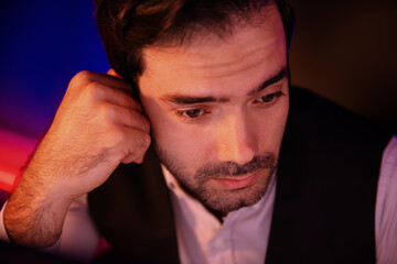 Portrait feeling bored businessman waiting analyzing market data or e-mail sending back to customer preparing created on sales channel online product at neon dark light at late night time. Surmise.