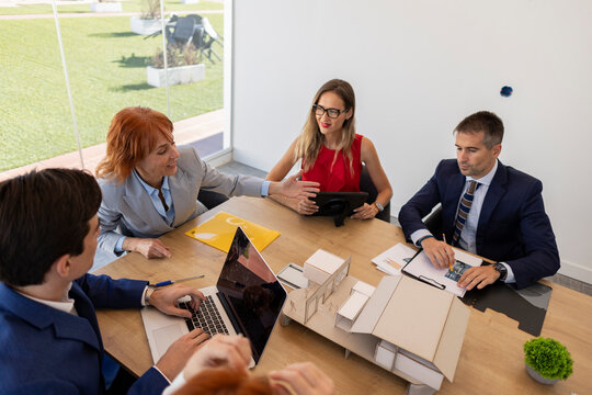 Architects having working meeting discussing around architectural model
