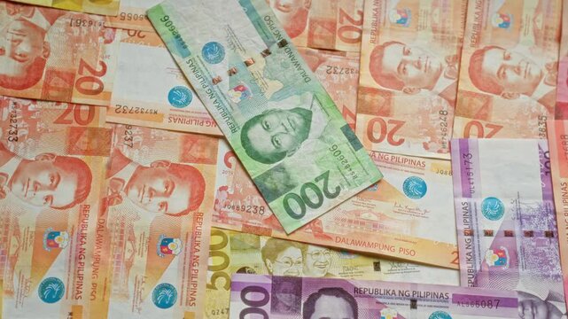 Various denominations of philippine pesos depicting different historical figures scattered in a close-up view emphasizing currency diversity and vibrant colors