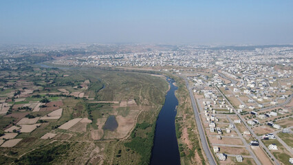 A high-angle view of the city’s main road next to a river belt, with nearby farmland, highlighting the connection between urban and rural areas.