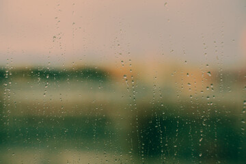 The window glass is covered in a thin layer of water from the rain. A hazy image of the landscape can be seen through it. This forms the backdrop.