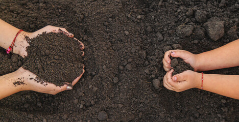 A child holds soil in his hands. Selective focus.